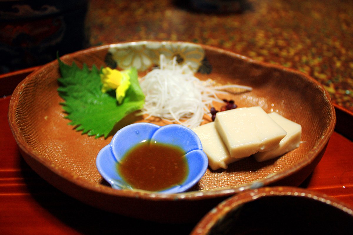 旅館の夕食。漆器や小皿に盛られた複数の料理が膳に並んでいる