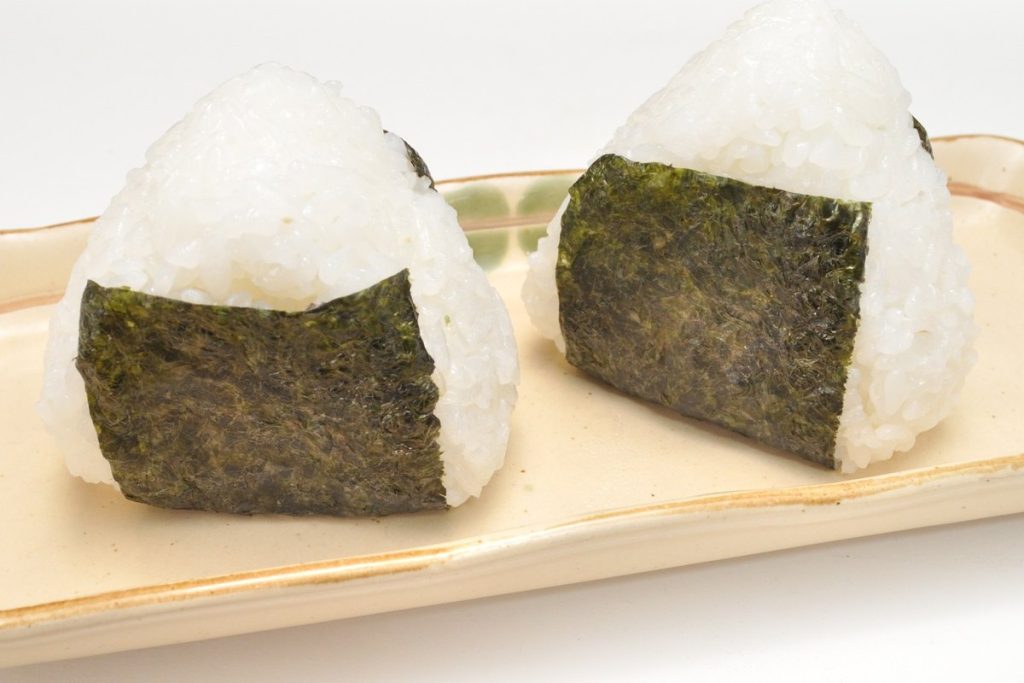 皿にのった海苔巻きのおにぎり二つ