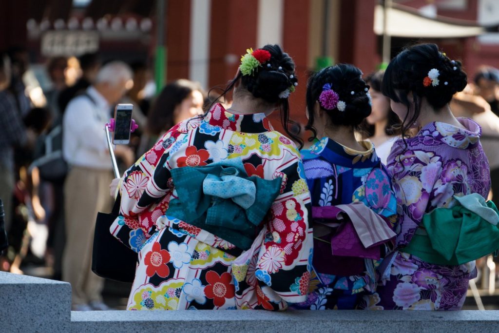 東京・浅草で、着物姿の三人が後ろ姿のままスマートフォンで自撮りをしている様子