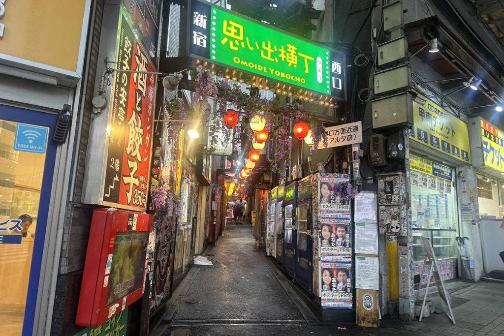 東京・新宿の思い出横丁で、小さな飲食店の看板やちょうちんが両側に並ぶ細い路地