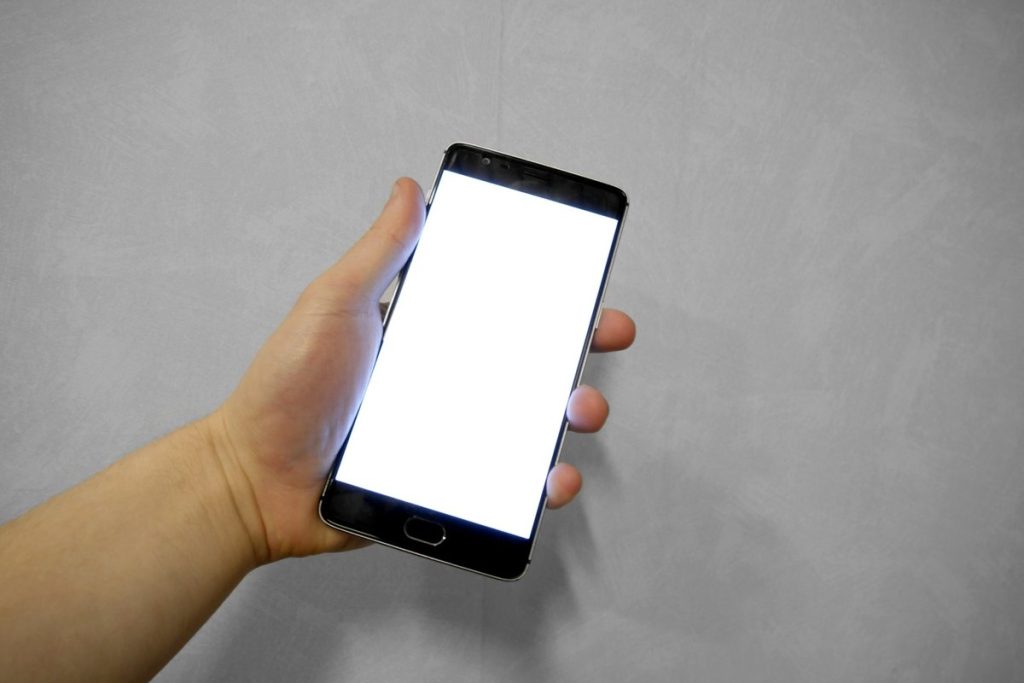 白い画面のスマートフォンを持つ手
