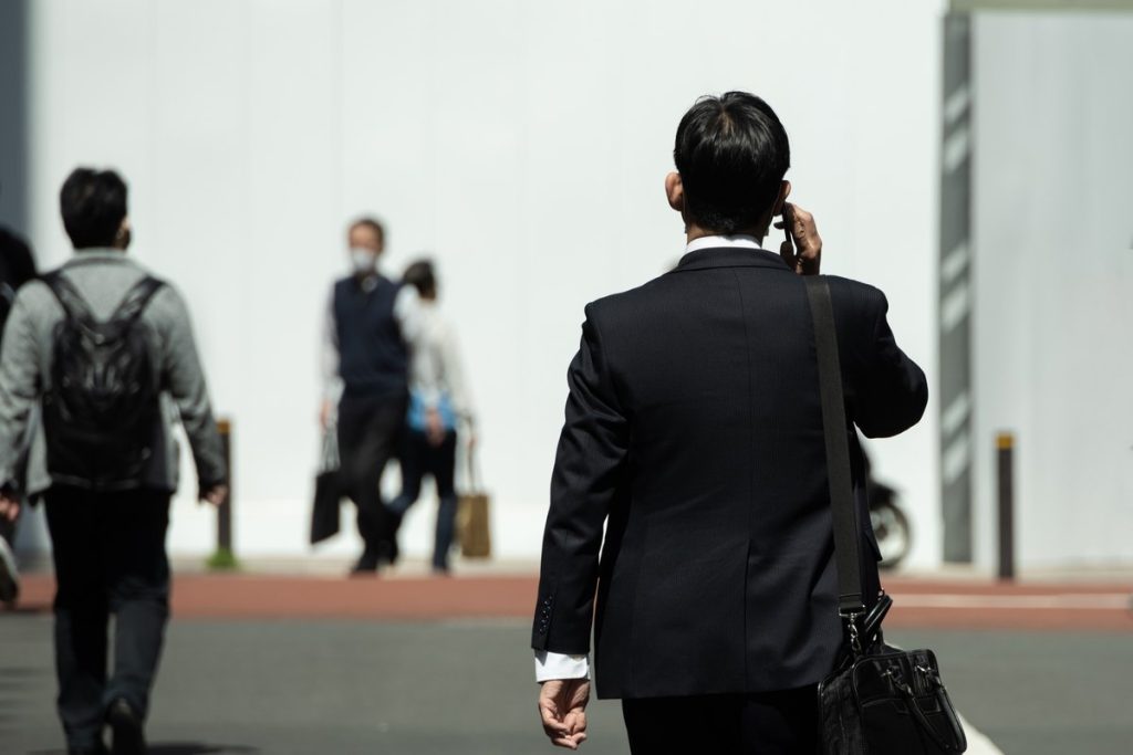 スーツ姿で電話をしながら歩く会社員の後ろ姿