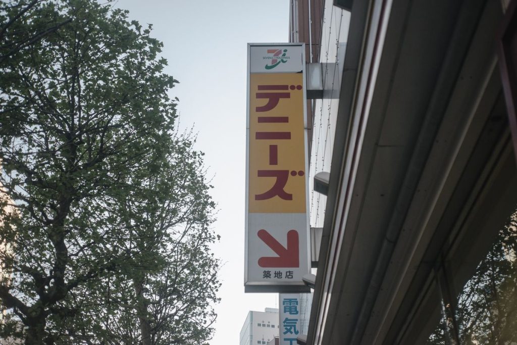 ファミリーレストランの店先に掲げられた縦長の看板と入口を示す矢印