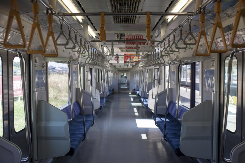 オレンジ色のつり革が並ぶ、首都圏を走るJR東日本の通勤電車の車内