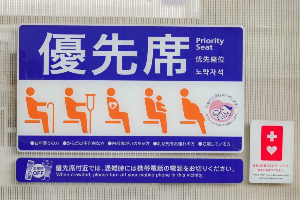 東武鉄道の電車に貼られた優先席のステッカー。お年寄りや妊娠している人などのピクトグラムと、マタニティマーク・ヘルプマークの案内