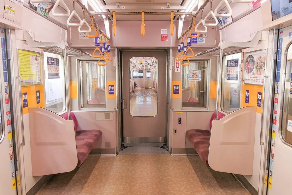 オレンジ色のつり革と優先席がある通勤電車の車内