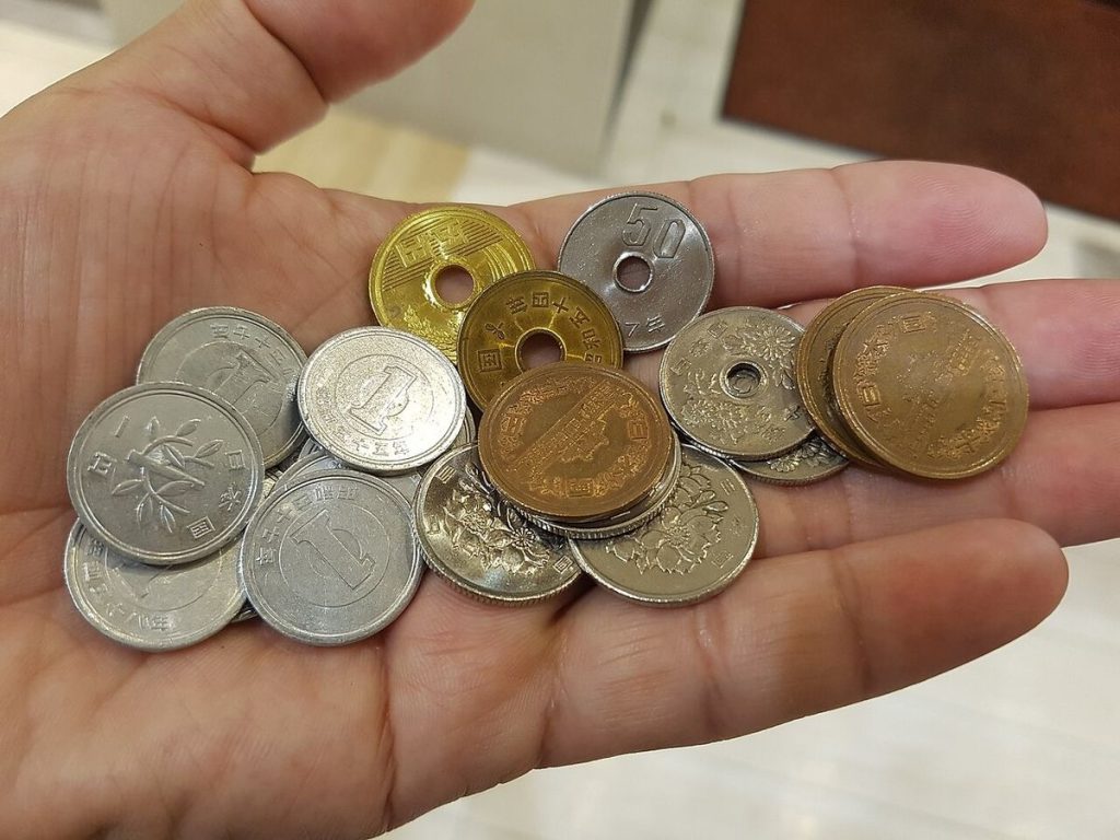 手のひらにのせた1円玉・5円玉・10円玉・50円玉・100円玉などの日本の硬貨